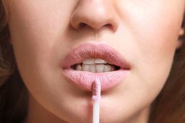 Naklejka premium Beautiful young woman applying lipstick, closeup