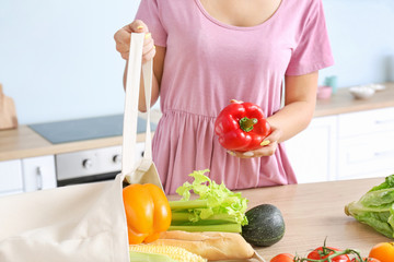 Woman taking products out of eco bag in kitchen