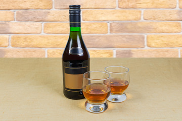 Two glasses and bottle of brandy on a textile surface