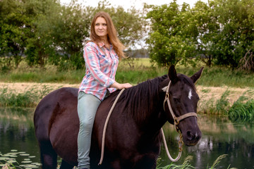 Fototapeta premium young woman sitting on her black horse