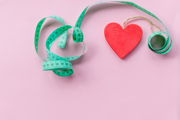 healthy heart. green measuring tape on pink background. Weight control concept. Patient health care, weight reduction program concept. Fitness design. overweight,excess weight