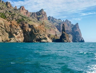 Coastal cliffs of volcanic origin on sea against of sky