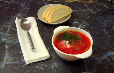 Traditional Russian red borsch with sour cream and cut greens. Close-up.