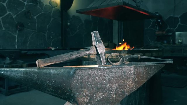 Hammer and tongs lying on anvil at a forge.