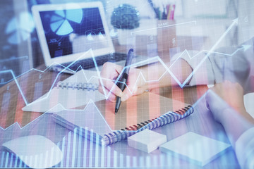 Financial charts displayed on woman's hand taking notes background. Concept of research. Double exposure