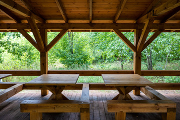 Fototapeta na wymiar Wooden Shelter With Tables in Park