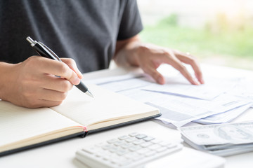 Stressed man calculating accounting holding a receipt checking bills, taxes, bank account balance counting money and making notes, check home expenses concept.