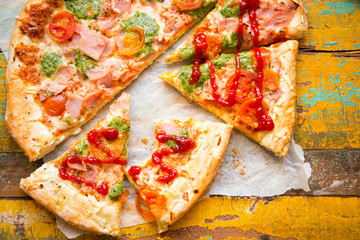 Pizza with parma ham, cheese, green pesto and tomatoes 