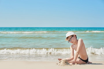 Child boy on beach. Rest on vacation, play in sand against sea. Tourism and vacation on ocean. Family vacation in summer. Vacation at sea. Summer travel.
