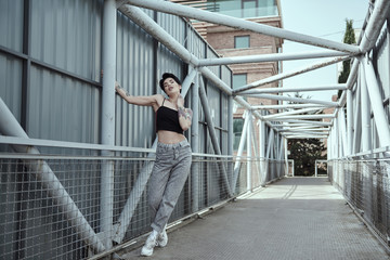 Raven haired young lady with tattoos posing on the bridge