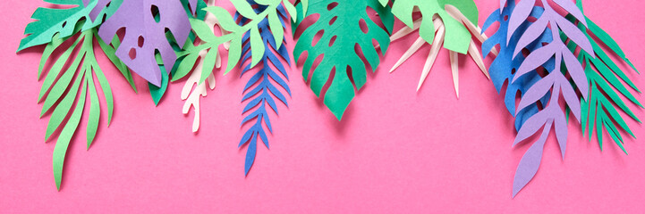 tropical leaves cut from paper on pink background.