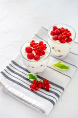 Two glasses with greek yogurt, raspberry and red currant