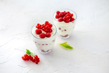 Two glasses with greek yogurt, raspberry and red currant
