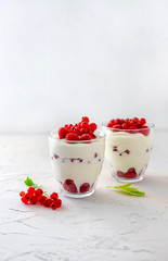 Two glasses with greek yogurt, raspberry and red currant