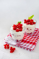 Two glasses with greek yogurt, raspberry and red currant