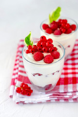 Two glasses with greek yogurt, raspberry and red currant