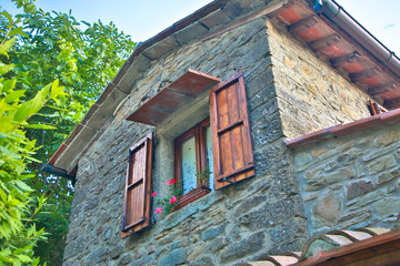 Fenster mit Klappläden und Blumen an einem  Backsteinhaus