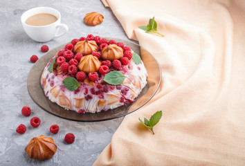 Homemade jelly cake with milk, cookies and raspberry on a gray concrete  background with cup of coffee and orange textile, side view.