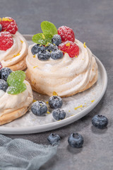 Mini pavlova meringue cakes with fresh raspberries and blueberries with mint leaves