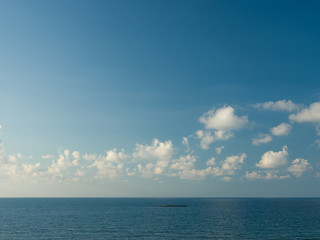 Fototapeta na wymiar Small rock in the sea. blue sky and white clouds