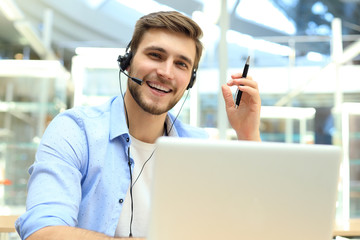 Happy young male customer support executive working in office.