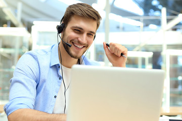 Happy young male customer support executive working in office.