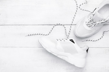 Scattered fashionable white sneakers on white wooden boards. Sport shoes. Stylish background....