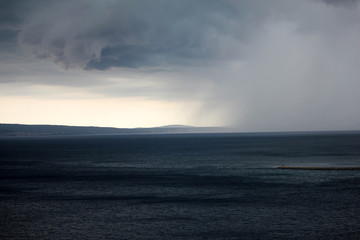 Supercell storm with dramatic dark cloud and rainstorm at the sea