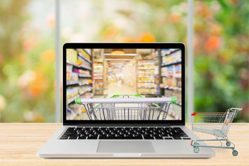 laptop computer and shopping cart on wood table with window and garden abstract blur background...