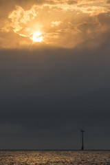 Standing against climate change. Solitary wind turbine at sunrise