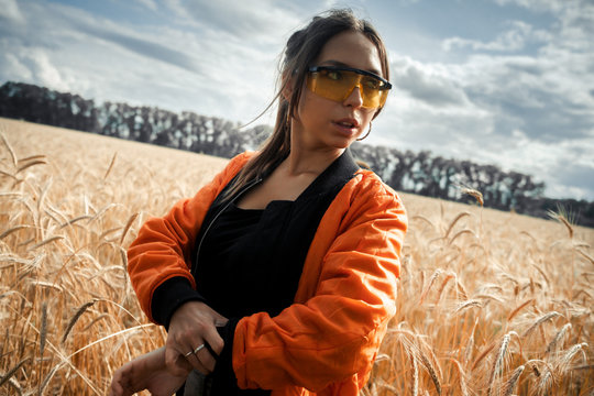 The girl in bright orange glasses and orange jacket.Bright girl.Girl in rye.Summer photos of a beautiful girl in the field.