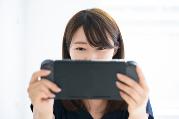携帯ゲーム機で遊ぶ女性