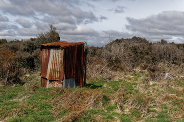 A rusty corrugated iron back country toilet or outhouse.