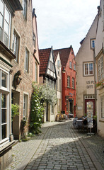 Fototapeta na wymiar Bremen, Germany - 07 23 2015 - Scenic view of medieval street Schnoor with half-timbered houses in the centre of the Hanseatic City, beautiful architecture, sunny day