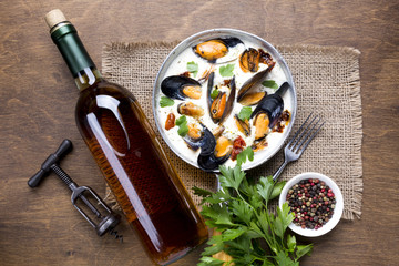 Flat-lay mussels in white sauce and wine bottle