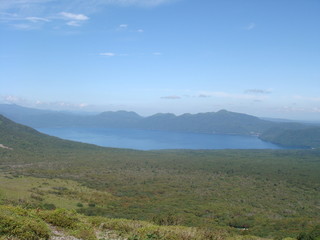 Wild mountains and lake Shikotsu in Hokkaido with blue sky and clouds and green trees in summer