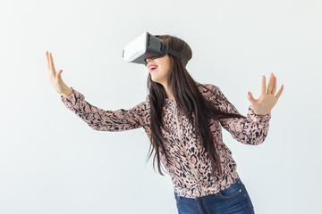 Young woman watches a movie with glasses of virtual reality standing on a white background. The...