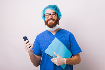 Portrait of smiling surgeon holding smartphone and paper work