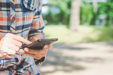 close up handsome man using hand typing mobile phones and touch screen working search with app devices outdoor in city with sunrise and building background.