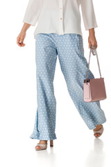 Naklejka premium woman wearing summer high heeled sandals in polka-dot blue pants and pink woman handbag on white background.