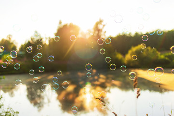 beautiful background with soap bubbles at sunset lake