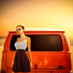 Naklejka premium Slim young woman in summer dress and orange retro car on beach. 