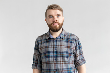 Fototapeta premium Young man with a mustache and beard making bulging eyes in surprise against a white background. Concept of surprise and uncertainty.