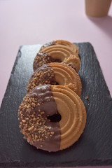  Aerial photo of chocolate covered cookies and almond chips on a black slate plate and a pink table in the background.
