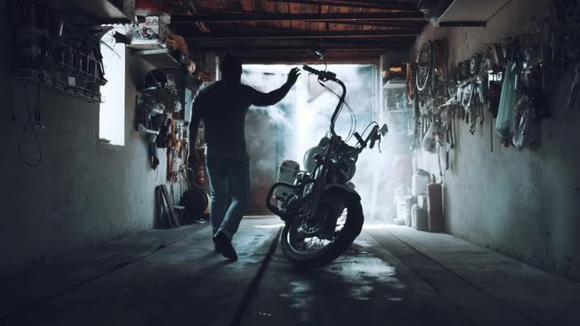 biker with a motorcycle in an atmospheric garage. a man sits on his iron horse and prepares to set off