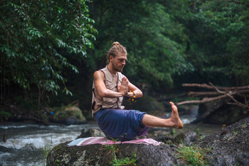 Yoga practice and meditation in nature. Man practicing near river