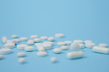 White medical pills on blue background.