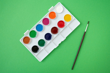 Top view of watercolor paint in box on green background