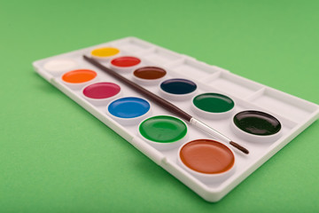 Top view of watercolor paint in box on green background