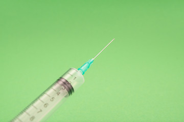 Medical syringe on green background, health and vaccination concept.